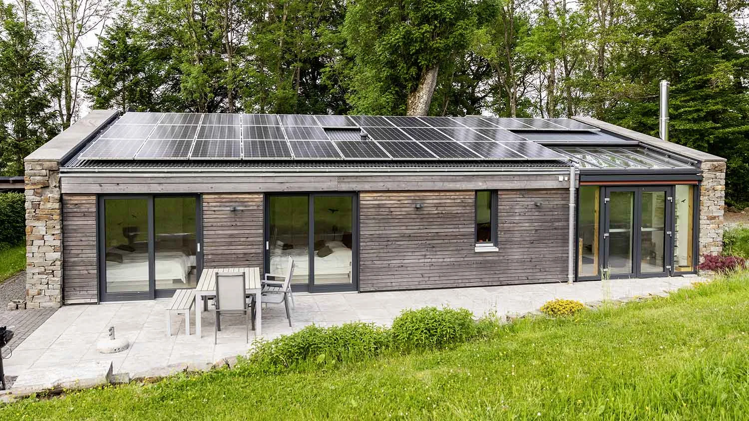 A home roof with solar panels set against a leafy landscape